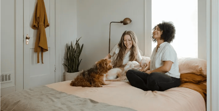 Two women and a dog sitting on a bed.
