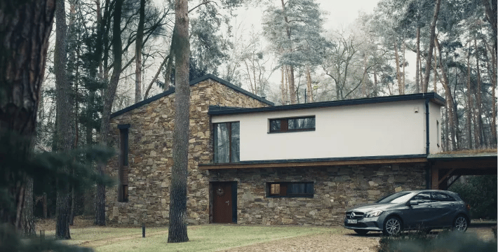 House surrounded by trees with a car parked in front