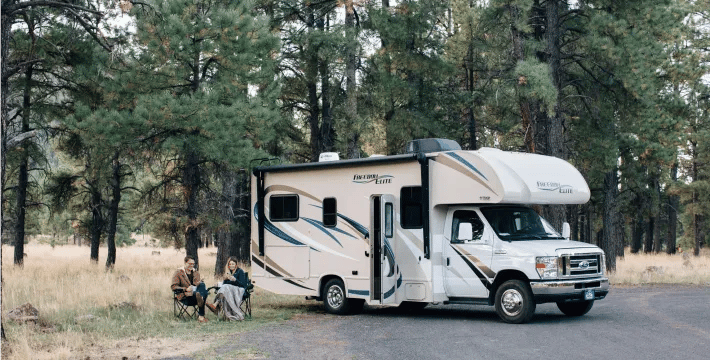 People sitting by a camper in the woods