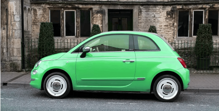 mint colored compact car parked in front of a building