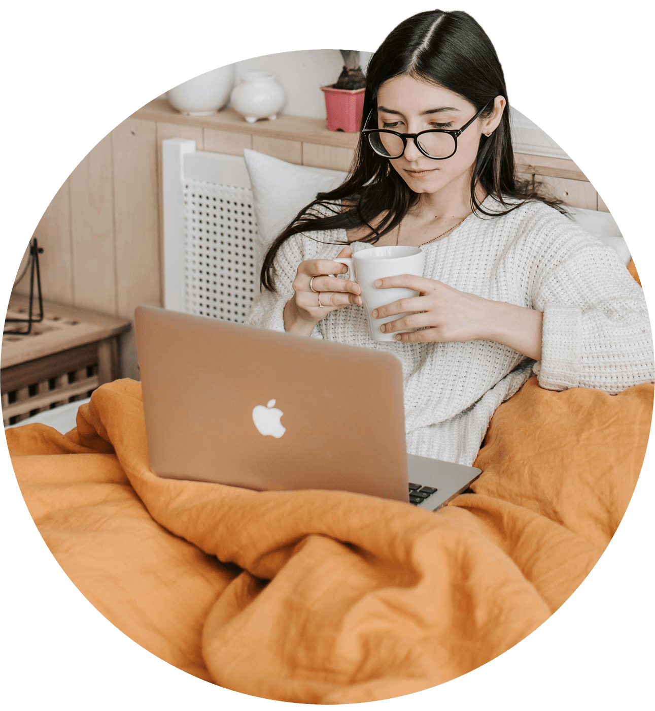 Young woman reading newsletter on laptop, while drinking a mug of coffee.