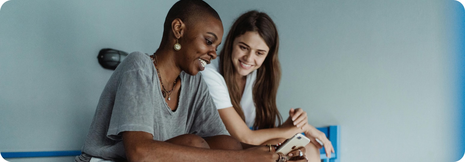 Two girls sitting on a bunkbed looking at one girl's phone